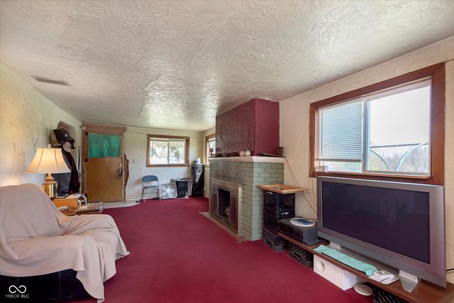 carpeted living area featuring a textured ceiling, visible vents, a textured wall, and a brick fireplace | Image 5