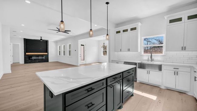 Kitchen with pendant lighting, a sink, white cabinets, light wood finished floors, and decorative backsplash | Image 18