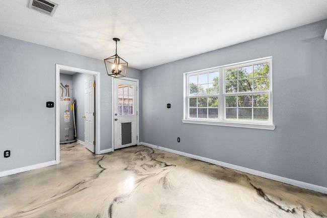 Unfurnished dining area featuring concrete flooring, electric water heater, and a chandelier | Image 21
