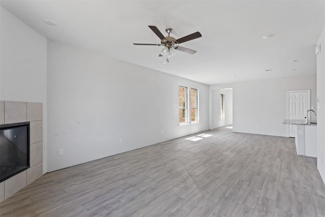 Unfurnished living room featuring light hardwood / wood-style floors, sink, a fireplace, and ceiling fan | Image 10