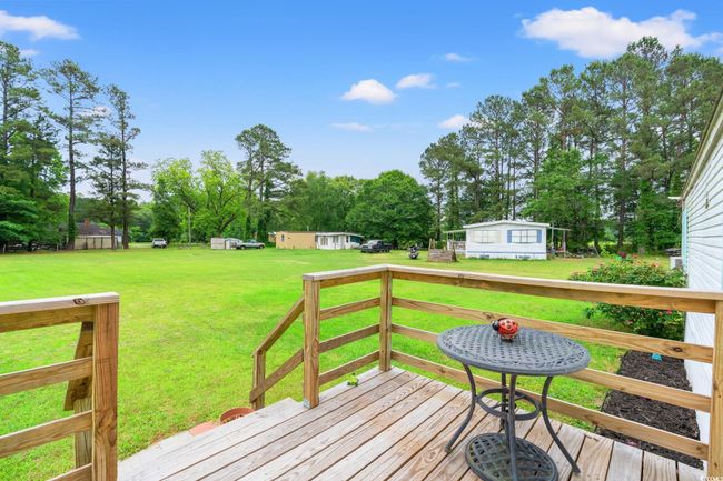 Wooden deck with a lawn and view of scattered trees | Image 4