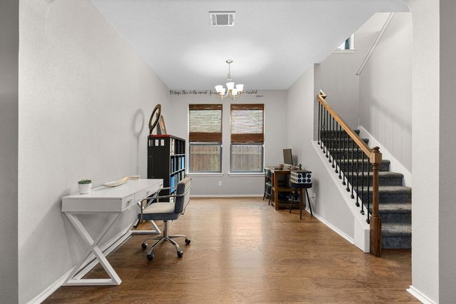 Home office with wood finished floors, a chandelier, and baseboards | Image 15