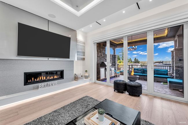 Living room featuring a glass covered fireplace, wood finished floors, and recessed lighting | Image 26