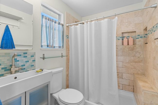 Full bath featuring a stall shower, toilet, decorative backsplash, and vanity | Image 31