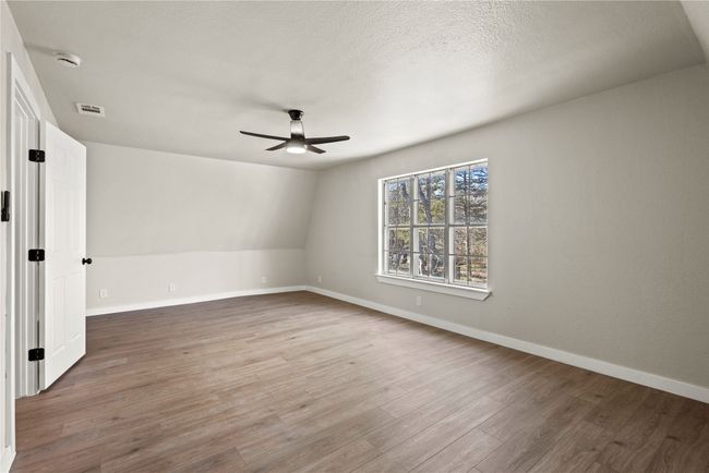 Unfurnished room with ceiling fan, a textured ceiling, wood finished floors, visible vents, and baseboards | Image 14
