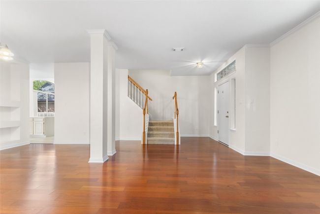 Unfurnished living room with stairs, wood finished floors, and built in features | Image 5