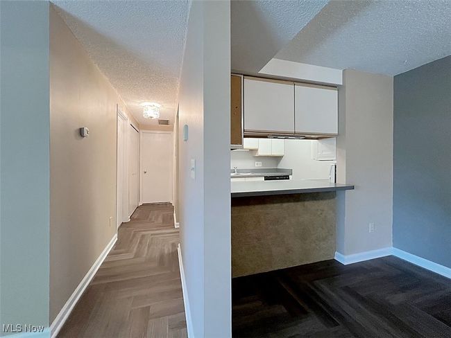 Hallway and Kitchen with a textured ceiling, white cabinets, and light countertops | Image 13