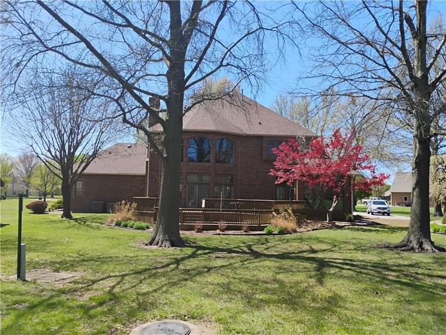 Back of property with a lawn, a wooden deck, brick siding, and roof with shingles | Image 9