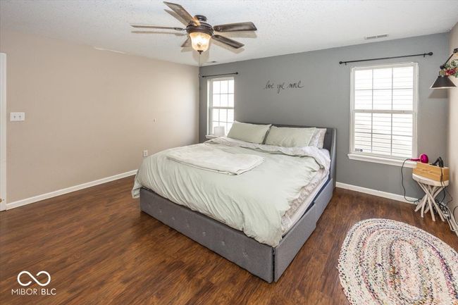 bedroom featuring a ceiling fan, wood finished floors, a textured ceiling, baseboards, and visible vents | Image 17