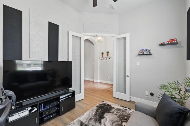 Living area with a ceiling fan, arched walkways, light wood finished floors, and french doors | Image 5