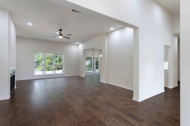 Unfurnished living room with a fireplace, ceiling fan, dark wood-type flooring, baseboards, and recessed lighting | Image 9