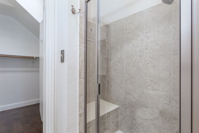 Full bath featuring a walk in closet, wood finished floors, lofted ceiling, and a stall shower | Image 19