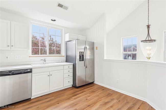 Kitchen with white cabinetry, appliances with stainless steel finishes, a sink, and visible vents | Image 12