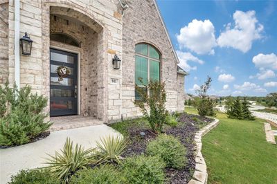 A covered front porch secludes the entry and a pair of coach lights illuminate the way for guests. The home is located on a raised corner lot next to a park and has an impressive view from the side. | Image 2