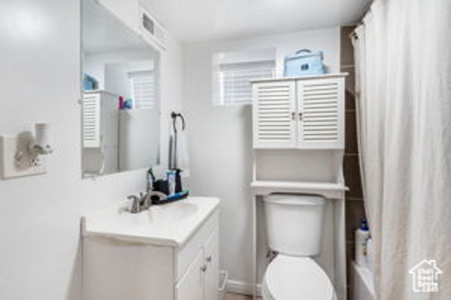 Full bath featuring a shower with shower curtain, toilet, vanity, baseboards, and visible vents | Image 25