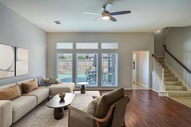 Floor to ceiling windows make for a light and bright family room which is open to the kitchen. Digitally staged. | Image 4