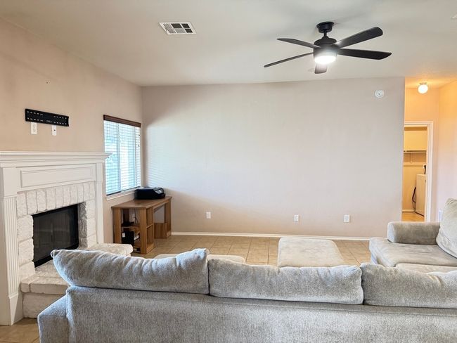 Living room featuring light tile patterned flooring, a ceiling fan, washer / dryer, and a fireplace | Image 8