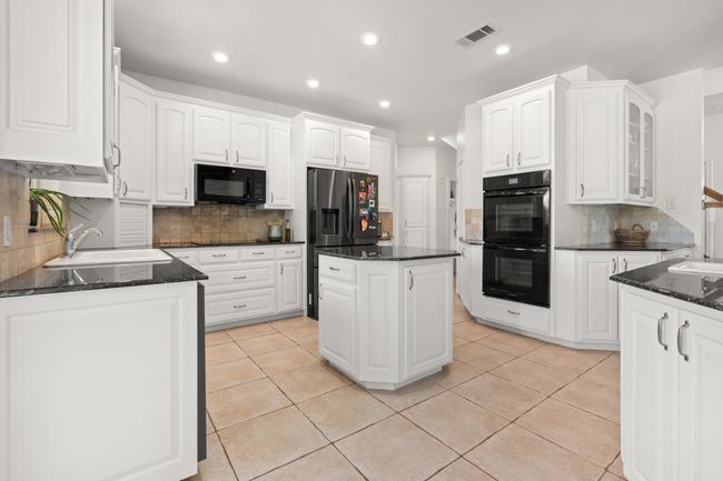 Open Concept Kitchen with black appliances, backsplash, double oven and extra sink | Image 12