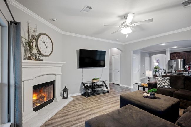 Living room with arched walkways, wood finished floors, ornamental molding, a ceiling fan, and baseboards | Image 8
