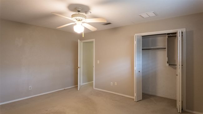 Unfurnished bedroom with a closet, baseboards, light carpet, visible vents, and ceiling fan | Image 34