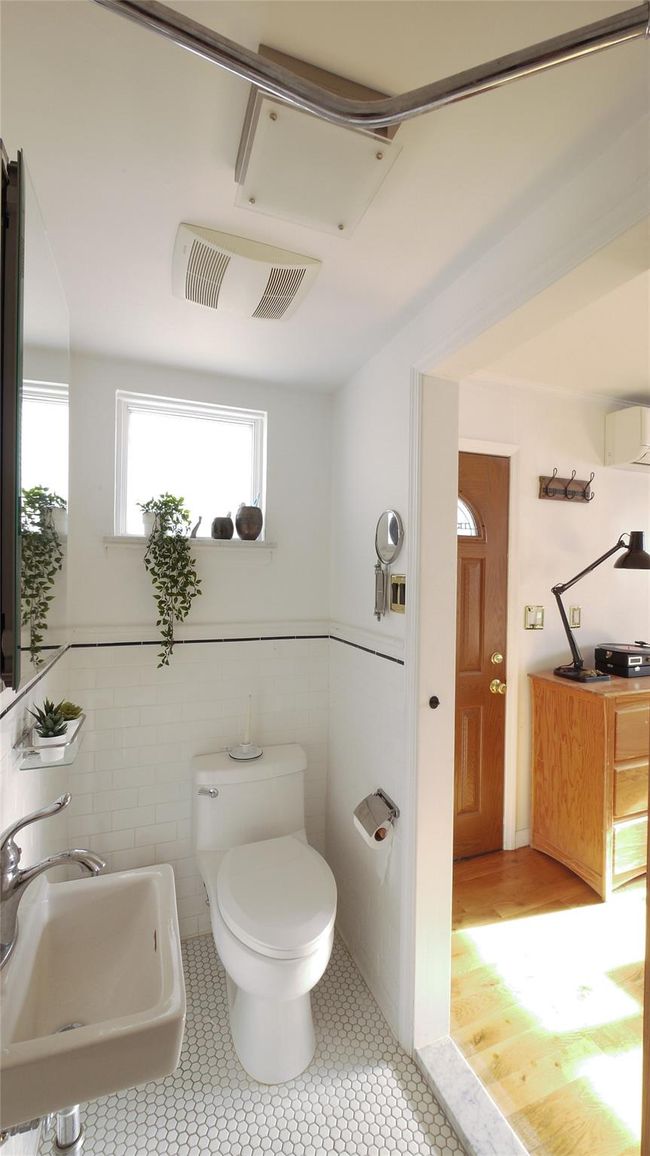 Half bath with a sink, toilet, an AC wall unit, tile patterned flooring, and tile walls | Image 17