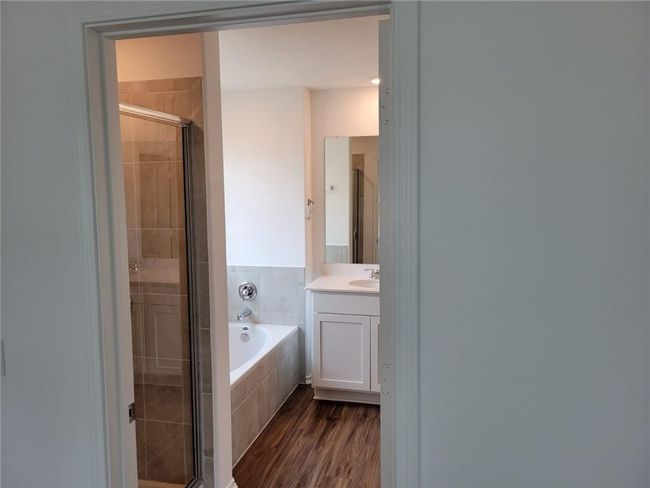 Bathroom with vanity, a stall shower, a bath, and wood finished floors | Image 24