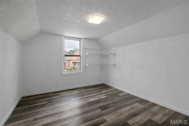 Bonus room featuring a textured ceiling, lofted ceiling, dark wood-style floors, and a textured wall | Image 13