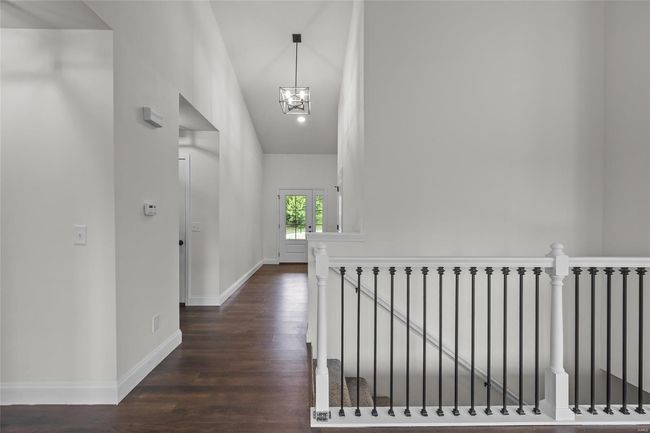 Hall featuring dark wood-style flooring, a notable chandelier, an upstairs landing, and baseboards | Image 33