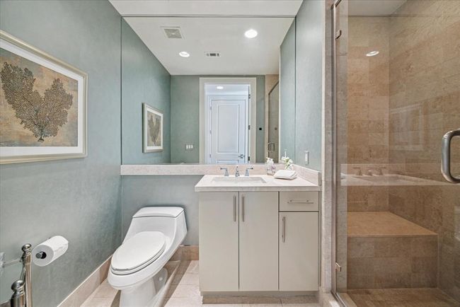 The secondary bathroom has custom wallpaper and a shower complete with a seat. | Image 26