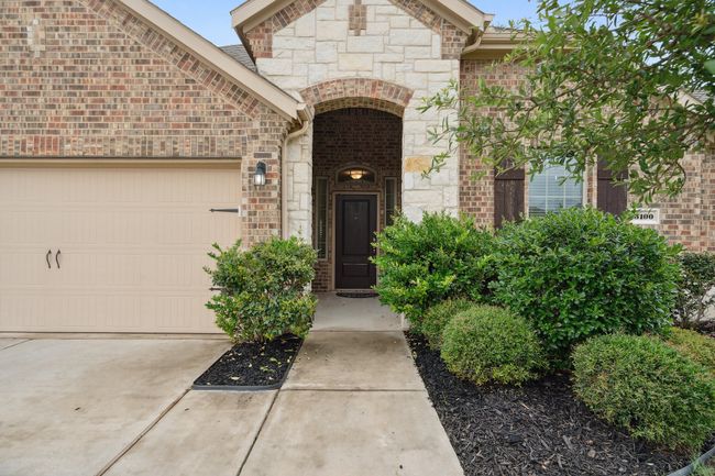 Property entrance with an attached garage, stone siding, brick siding, and driveway | Image 6