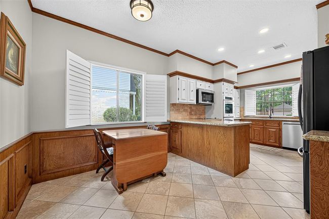 Unified by a harmonious wood aesthetic, this kitchen and breakfast area feels grounded and warm. A peninsula offers subtle separation, keeping conversations flowing between spaces. | Image 18
