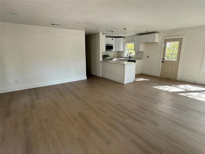 Unfurnished living room with light hardwood / wood-style flooring, a textured ceiling, and sink | Image 2