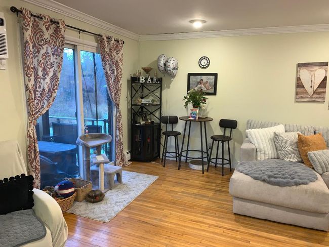 Living room featuring crown molding and wood finished floors with door to deck overlooking grass and trees | Image 5