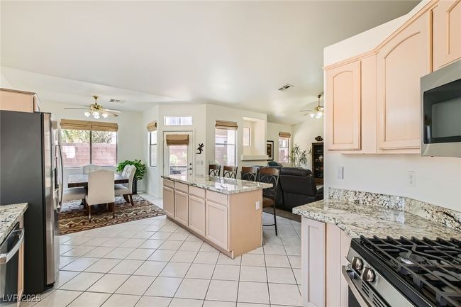 Kitchen featuring ceiling fan, stainless steel appliances, light tile patterned flooring, and open floor plan | Image 11