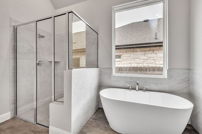 Full bathroom featuring a stall shower, a freestanding bath, and tile walls | Image 18
