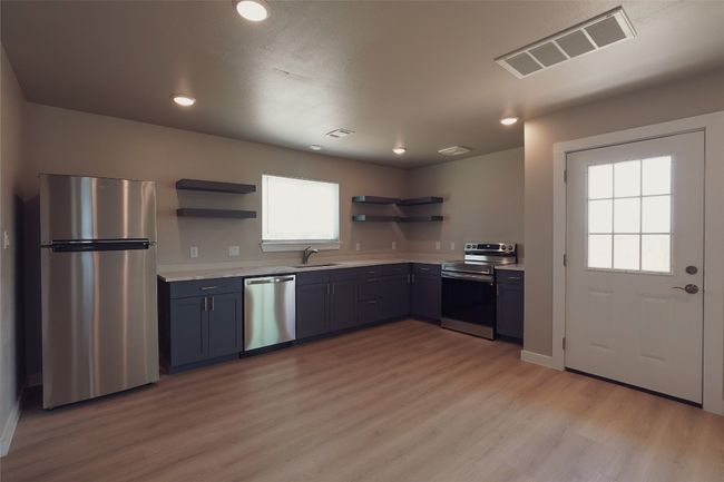Kitchen featuring stainless steel appliances, open shelves, light countertops, light wood finished floors, and recessed lighting | Image 8