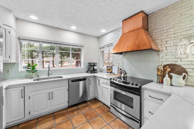 Kitchen with tasteful backsplash, premium range hood, stainless steel appliances, white cabinetry, and a sink | Image 14