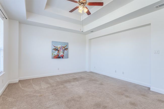 Spare room featuring visible vents, light carpet, a raised ceiling, baseboards, and ceiling fan | Image 23