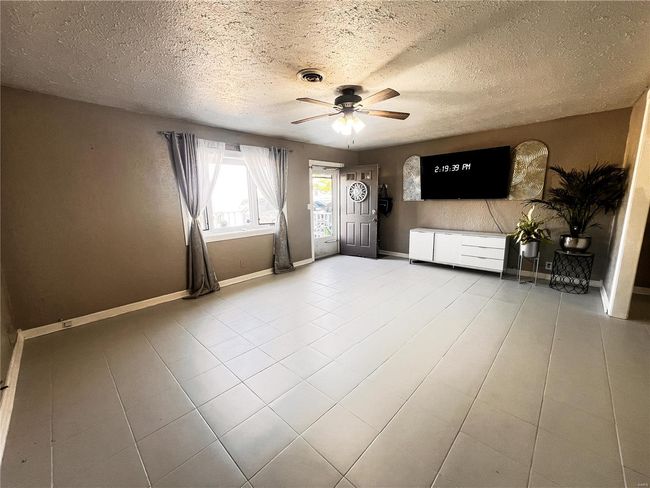 Unfurnished living room with a ceiling fan, tile patterned flooring, visible vents, and baseboards | Image 10