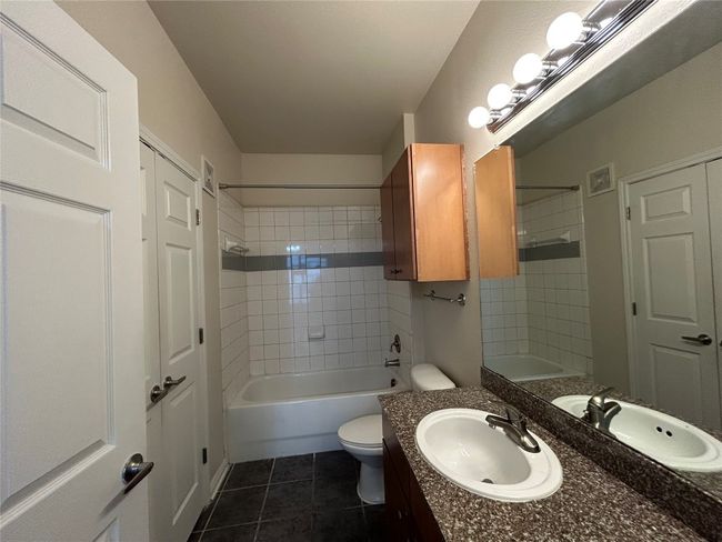 Bathroom featuring visible vents, toilet, tile patterned flooring, vanity, and washtub / shower combination | Image 12