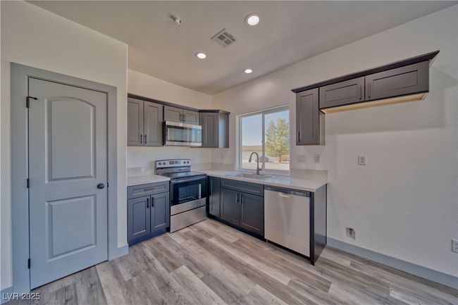Modern kitchen with sparkling quartz countertops, custom Onyx soft-close cabinets, fully pantry, and an open layout perfect for entertaining. | Image 6