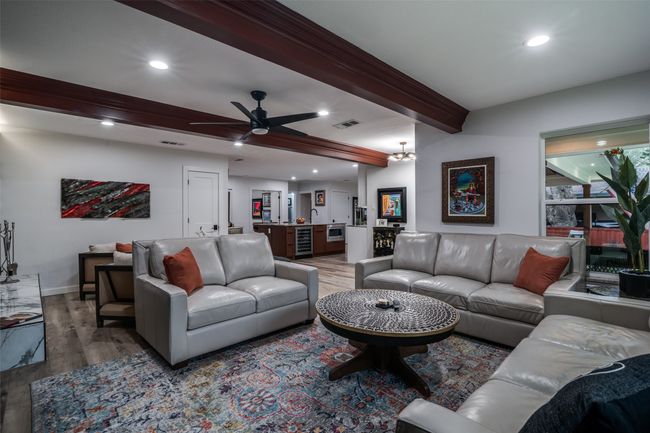 Living room with wood finished floors, beam ceiling, recessed lighting, ceiling fan, and wine cooler | Image 7