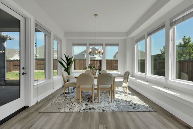 Sunroom featuring baseboards, wood finished floors, a wealth of natural light, and a chandelier | Image 13