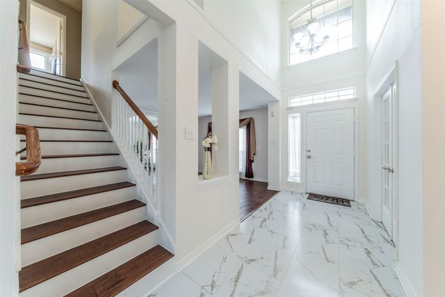 Entryway featuring marble look tiles, stairway, a high ceiling, and a chandelier | Image 20