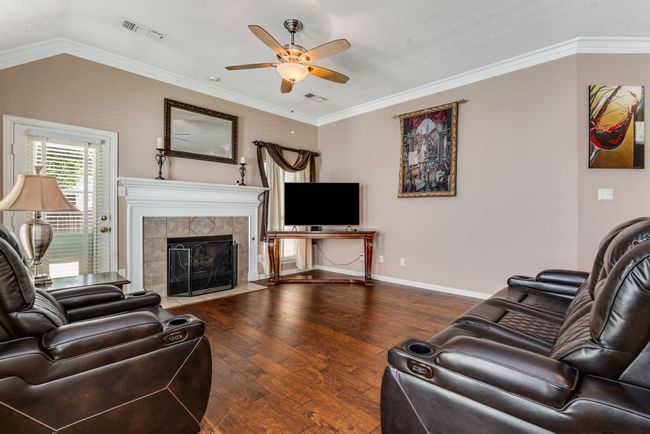 Living room with a ceiling fan, hardwood flooring, a tiled gas log fireplace, baseboards, and ornamental crown molding | Image 20