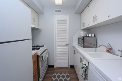 Kitchen with sink, dark hardwood / wood-style flooring, white appliances, and white cabinets | Image 2