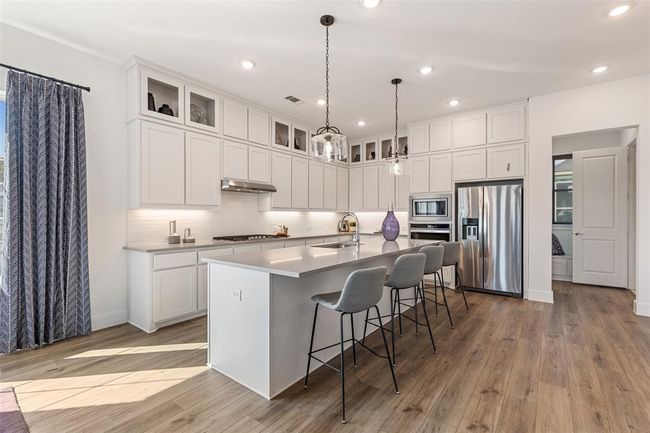 Kitchen featuring appliances with stainless steel finishes, a center island with sink, wood-type flooring, white cabinets, and sink | Image 14