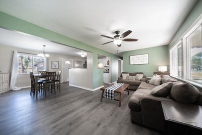 Living room with a textured ceiling, ceiling fan with notable chandelier, and dark hardwood / wood-style floors | Image 3