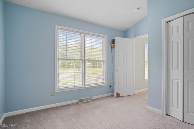 Unfurnished bedroom with carpet floors, multiple windows, baseboards, a closet, and vaulted ceiling | Image 6