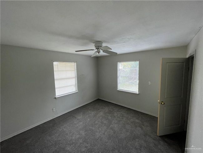Empty room featuring dark carpet, a ceiling fan, and baseboards | Image 14